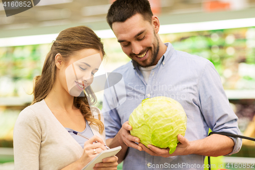 Image of couple with notebook and cabbage at grocery store
