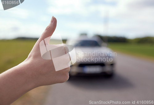 Image of hitchhiker stopping car with thumbs up hand sign