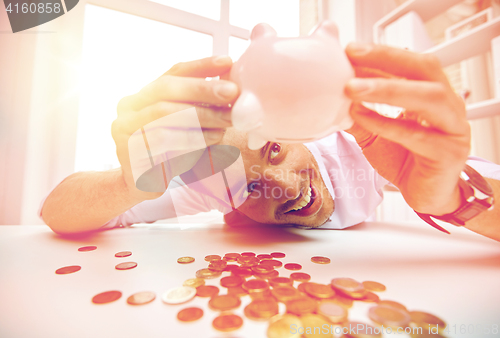 Image of businessman with piggy bank and coins at office