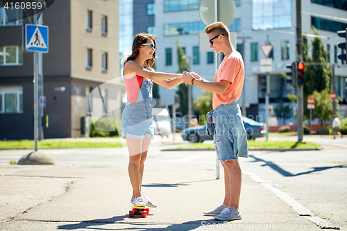 Image of teenage couple riding skateboards on city street