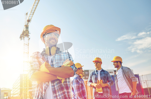 Image of group of smiling builders in hardhats outdoors