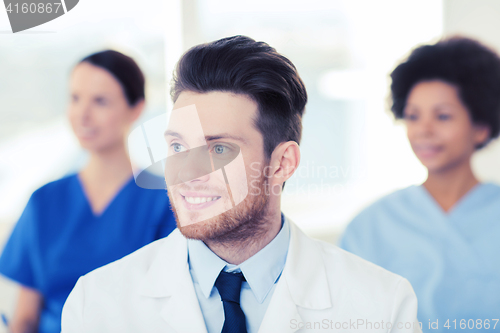 Image of happy doctor over group of medics at hospital