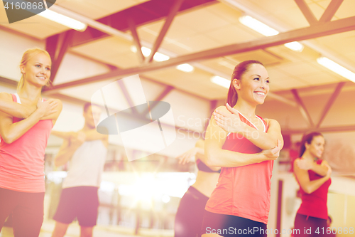 Image of group of smiling people stretching in the gym