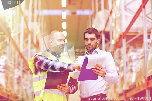 Image of worker and businessmen with clipboard at warehouse