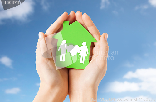 Image of hands holding green house with family pictogram