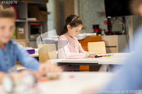 Image of happy girl building robot at robotics school