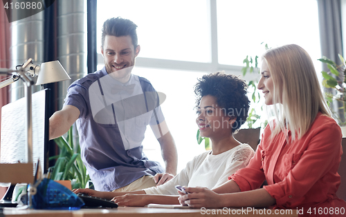 Image of happy creative team with computer in office