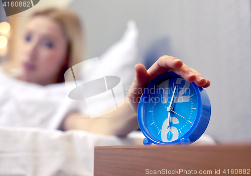 Image of close up of hand on alarm clock in bedroom