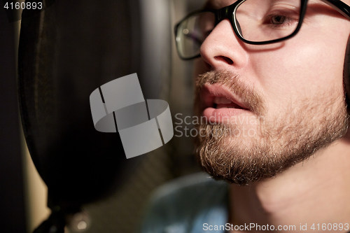 Image of man with headphones singing at recording studio