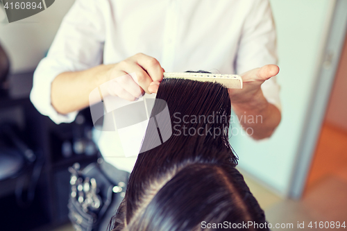 Image of male stylist hands combing wet hair at salon