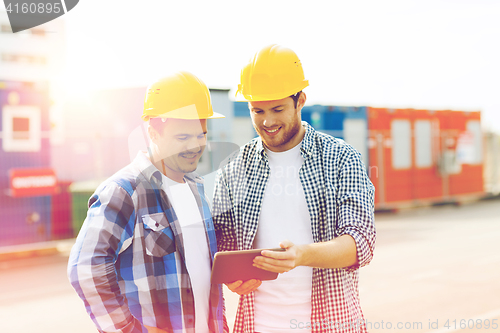 Image of two smiling builders in hardhats with tablet pc