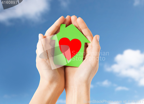 Image of hands holding green paper house with heart shape