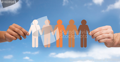 Image of hands holding chain of people pictogram over sky