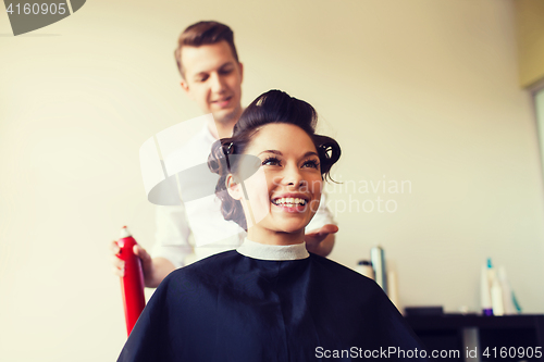 Image of happy woman with stylist making hairdo at salon