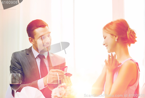 Image of man proposing to his girlfriend at restaurant