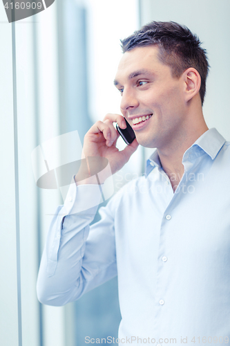 Image of smiling businessman with smartphone in office