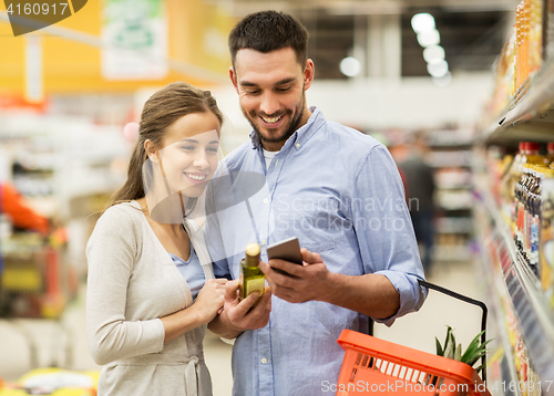 Image of couple with smartphone buying olive oil at grocery