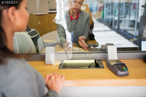 Image of clerk with cash money and customer at bank office