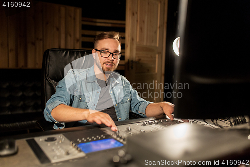 Image of man at mixing console in music recording studio