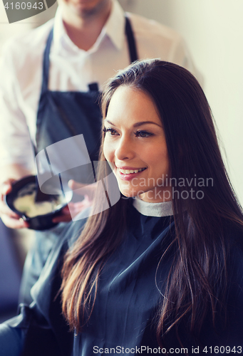 Image of happy young woman coloring hair at salon