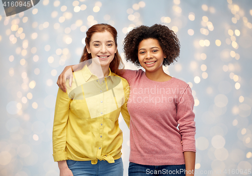 Image of happy smiling women hugging over holidays lights