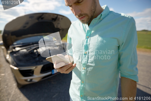 Image of close up of man with smartphone and broken car