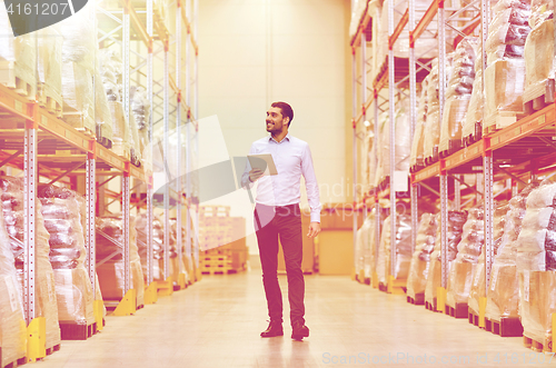 Image of happy businessman with tablet pc at warehouse