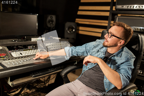 Image of man at mixing console in music recording studio