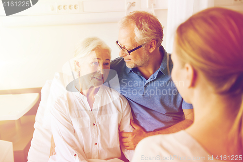 Image of happy family visiting senior woman at hospital