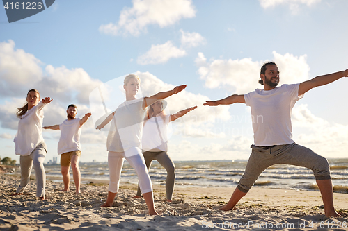 Image of group of people making yoga exercises on beach