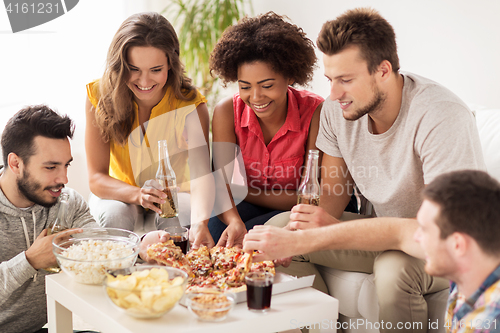 Image of happy friends with drinks eating pizza at home