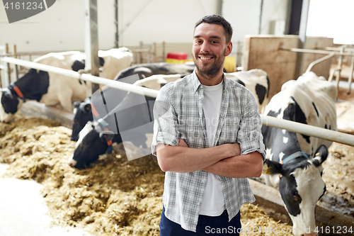 Image of man or farmer with cows in cowshed on dairy farm