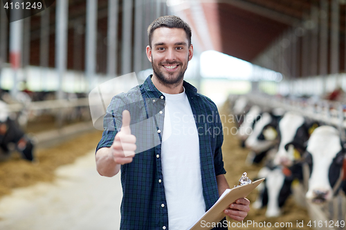 Image of farmer with cows showing thumbs up on dairy farm