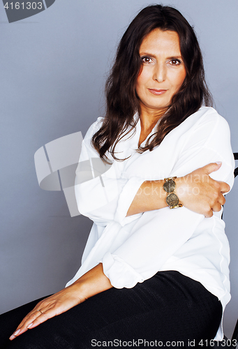 Image of pretty brunette confident mature woman sitting on chair in studio, lifestyle people concept 