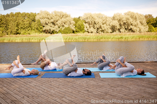 Image of group of people making yoga exercises outdoors