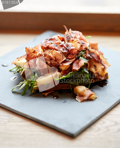 Image of prosciutto ham salad on stone plate at restaurant