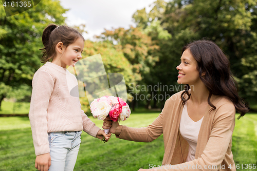 Image of girl giving with flowers to mother in summer park