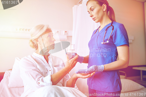 Image of nurse giving medicine to senior woman at hospital