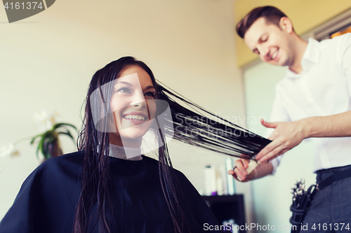 Image of happy woman with stylist cutting hair at salon