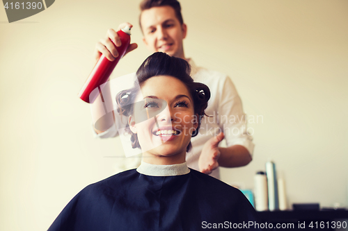 Image of happy woman with stylist making hairdo at salon