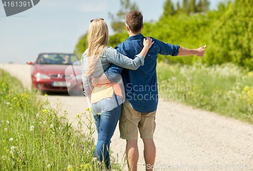 Image of couple hitchhiking and stopping car on countryside