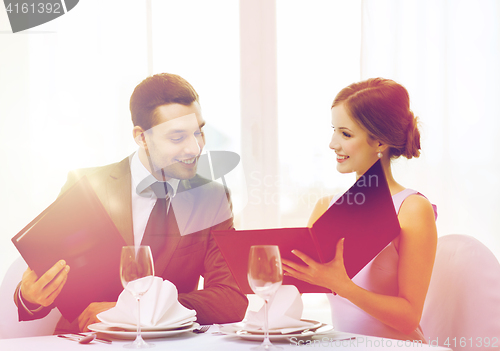 Image of smiling couple with menus at restaurant