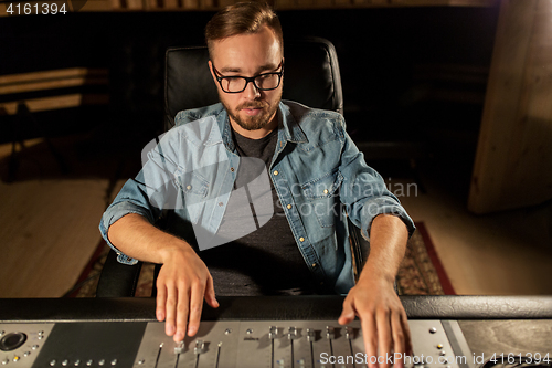 Image of man at mixing console in music recording studio