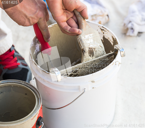 Image of Professional Painter Loading Paint Onto Brush From Bucket