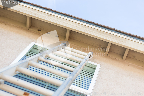 Image of Construction Ladder Leaning Against House