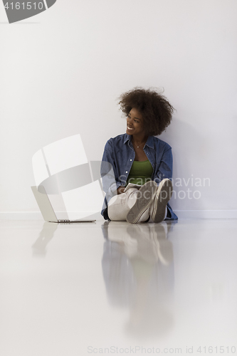 Image of african american woman sitting on floor with laptop