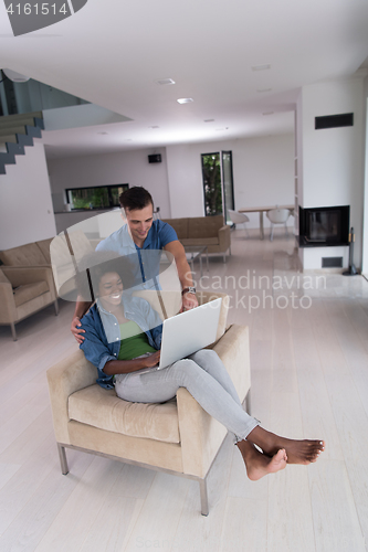 Image of multiethnic couple on an armchair with a laptop