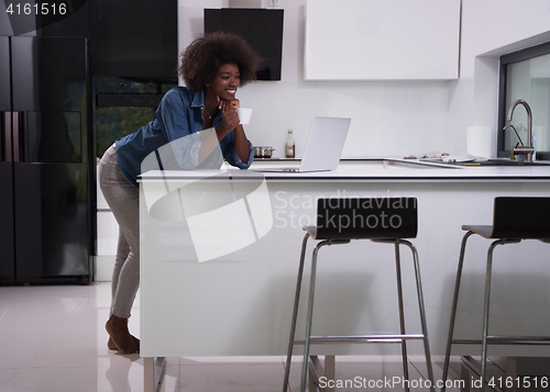 Image of smiling black woman in modern kitchen