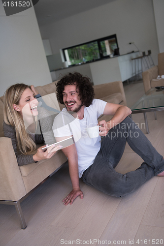 Image of couple relaxing at  home with tablet computers