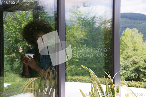 Image of African American woman drinking coffee looking out the window